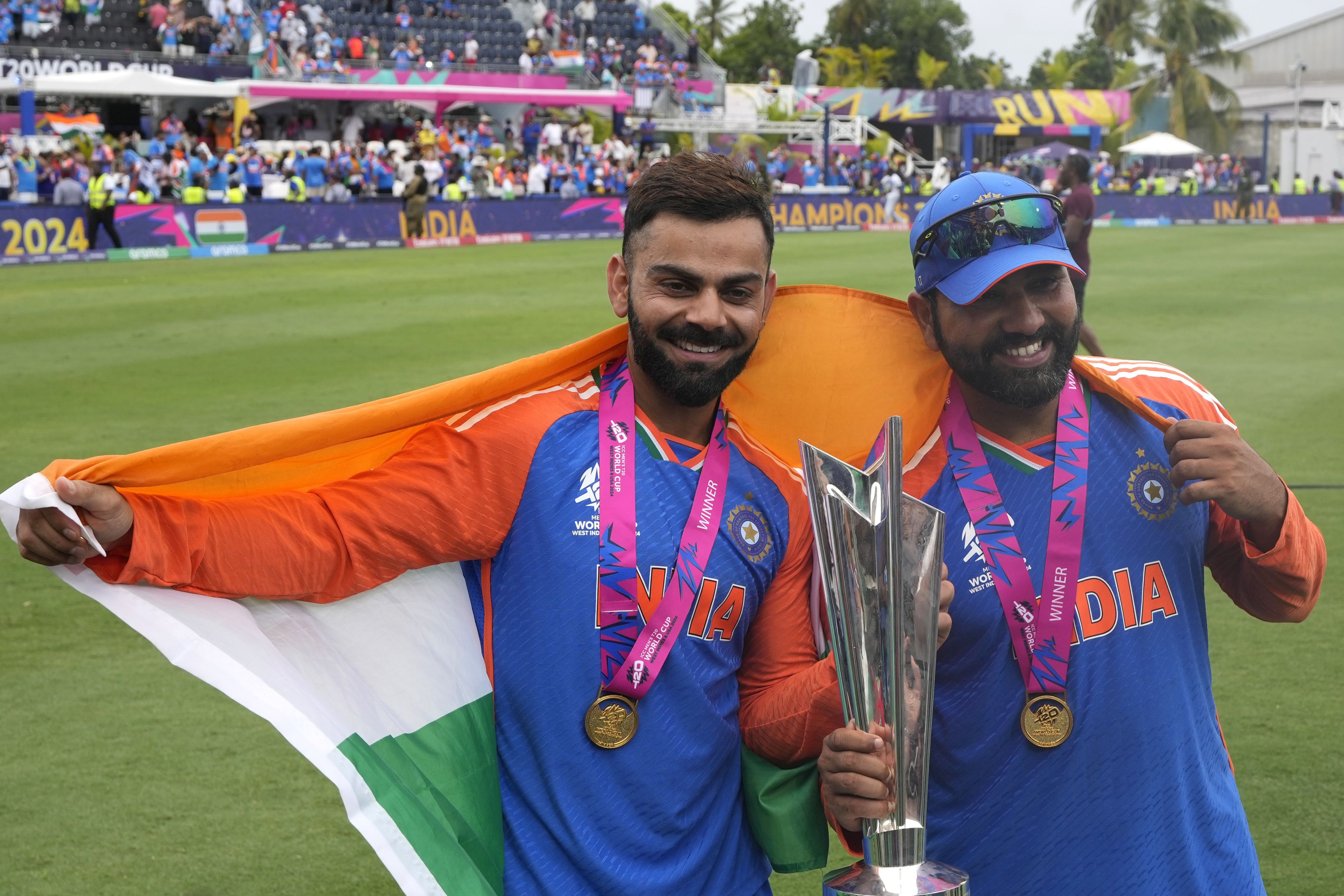 India's Virat Kohli, left, and captain Rohit Sharma pose with the winners trophy after defeating South Africa in the ICC Men's T20 World Cup final cricket match at Kensington Oval in Bridgetown, Barbados, Saturday, June 29, 2024. Credit: AP/PTI Photo