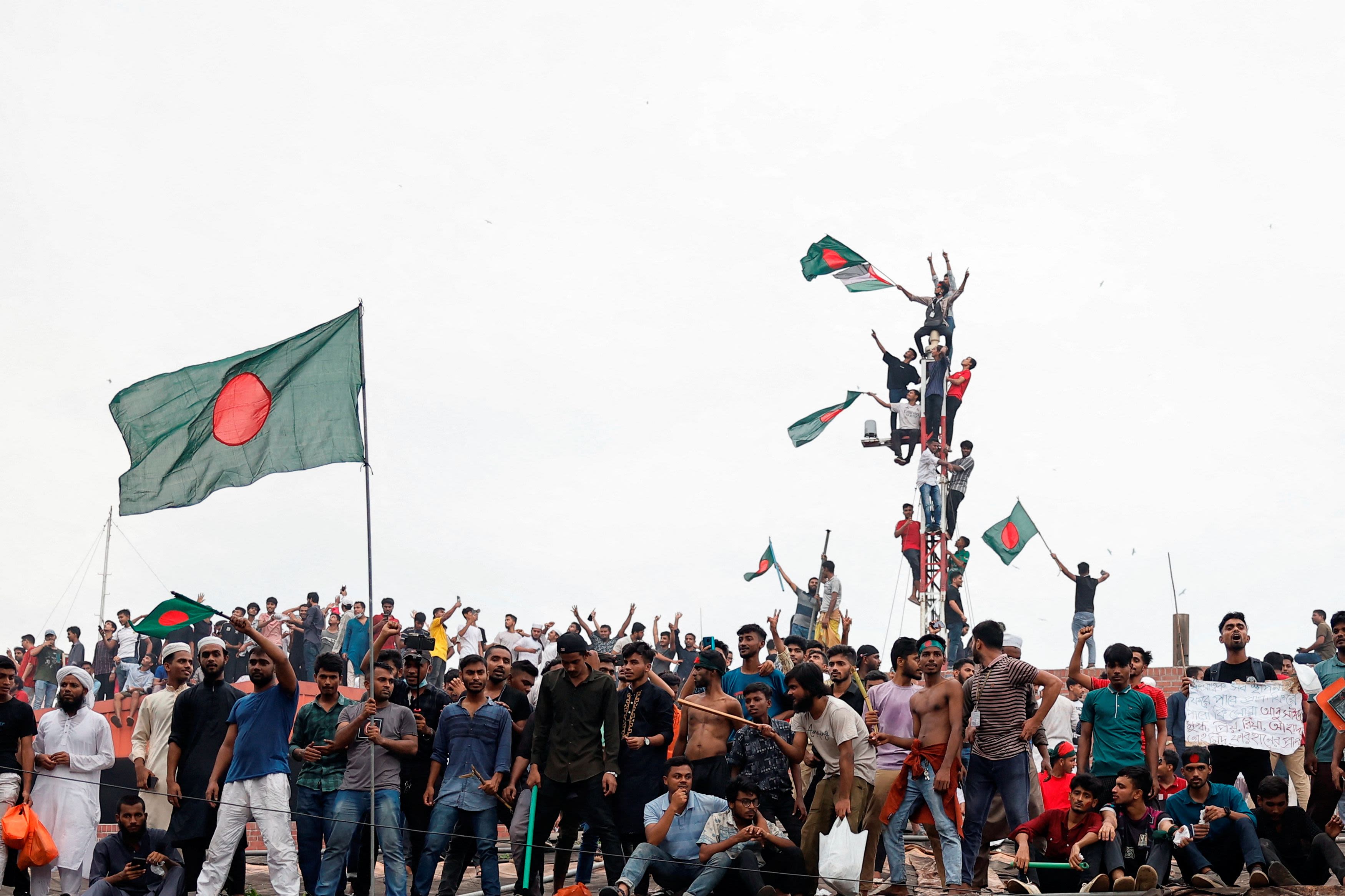 People wave Bangladeshi flags on top the Ganabhaban, the Prime Minister's residence, as they celebrate the resignation of PM Sheikh Hasina in Dhaka, Bangladesh, August 5, 2024. Credit: Reuters File Photo