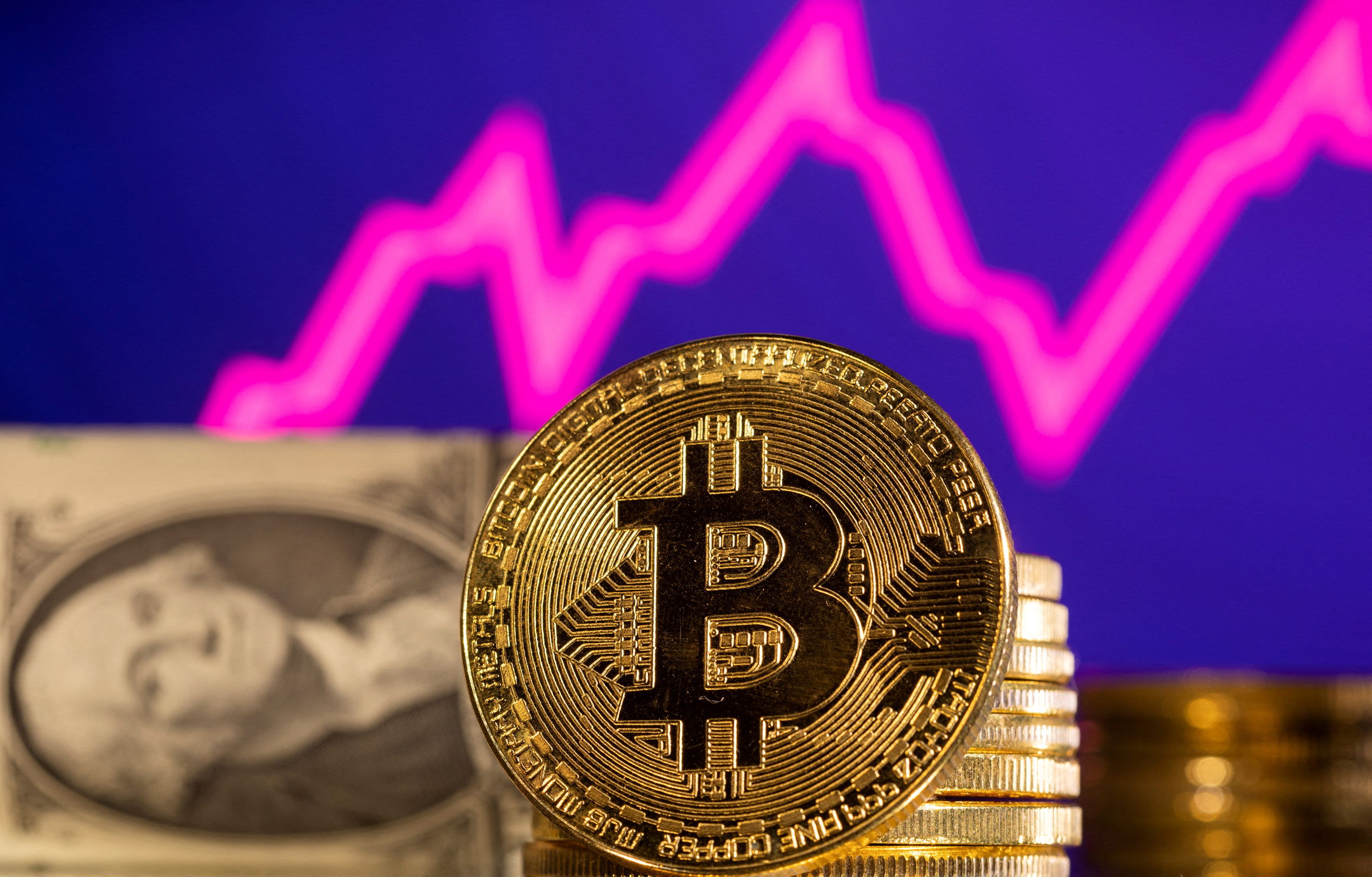 A representation of cryptocurrency bitcoin is seen in front of a stock graph and U.S. dollar in this illustration taken, January 24, 2022. Credit: Reuters File Photo