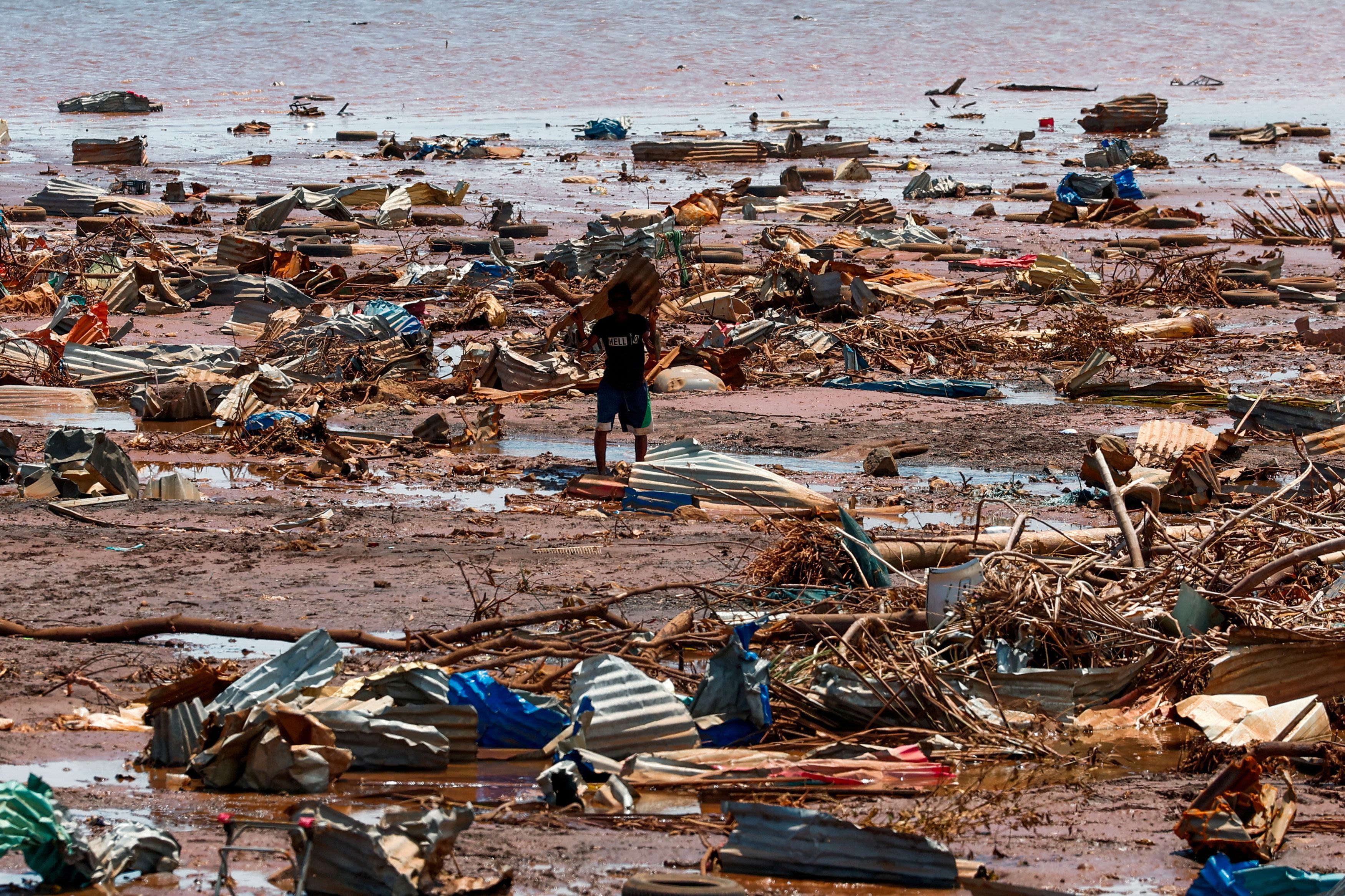 A boy carries a roofing sheet on the beach in the aftermath of Cyclone Chido, in Passamainty, Mayotte, France December 20, 2024. Credit: Reuters Photo